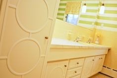 a bathroom with white cabinets and yellow walls