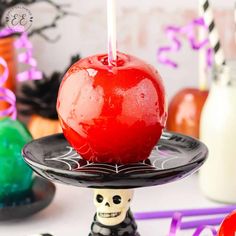 an apple sitting on top of a cake plate with a candle in the shape of a skeleton