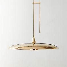 a gold colored pendant light hanging from a ceiling fixture in a white room with no one around it