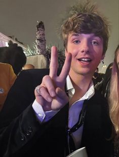 two people standing next to each other making the peace sign