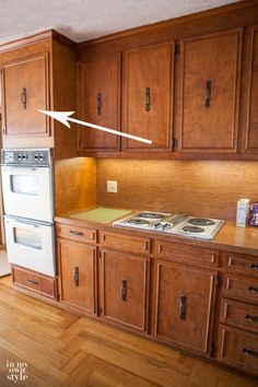 an empty kitchen with wooden cabinets and white stove top in the center, on hard wood flooring