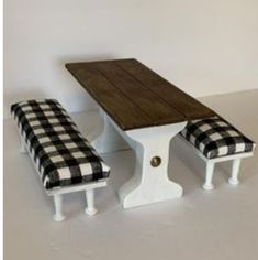 a wooden table and two benches with checkered cushions on the seat covers, against a white wall