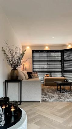 a living room filled with furniture next to a window covered in shades of black and white