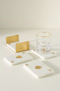 three coasters with gold foil designs on them and a glass in the foreground