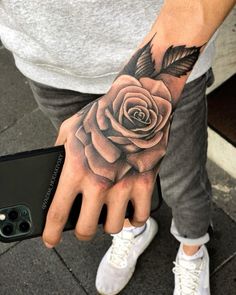 a man's hand with a rose tattoo on it and a feather in the middle