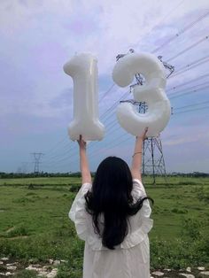 a woman holding up an inflatable number balloon