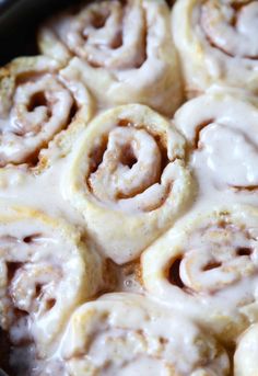 cinnamon rolls with icing sitting in a pan