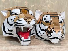 two paper sculptures of tigers with their mouths open