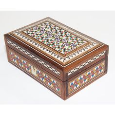 an ornate wooden box with colorful designs on the lid and sides, sitting on a white surface