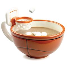 an orange and white bowl filled with food on top of a wooden table next to a cell phone