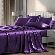 a bed covered in purple sheets and pillows