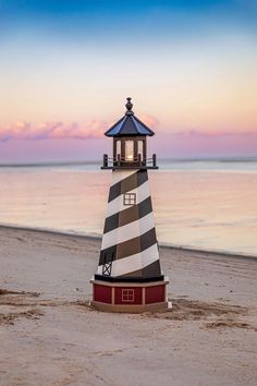 a light house on the beach at sunset with water in the backgroung