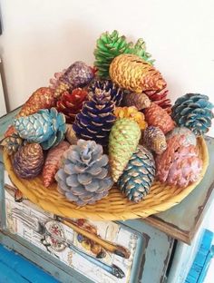 a basket filled with lots of pine cones on top of a blue dresser next to a white wall