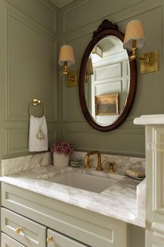 a bathroom sink sitting under a mirror next to a wall mounted faucet in a bathroom