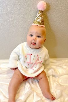 a baby wearing a birthday hat on top of a bed