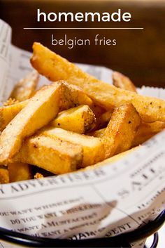 a basket filled with french fries sitting on top of a table next to a newspaper