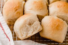 several rolls on a cooling rack with one cut in half and the other partially eaten