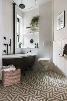 a bathroom with a black and white bathtub next to a toilet under a mirror