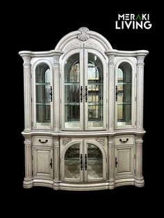 a white china cabinet with glass doors on the top and bottom, in front of a black background