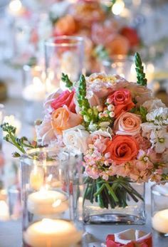 an arrangement of flowers in vases on a table next to candles and other decorations