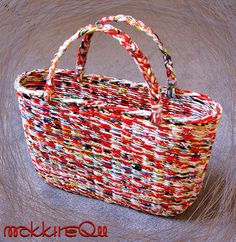 a multicolored woven basket with handles on the floor next to a brown background