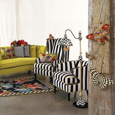 a living room with black and white striped chairs, yellow couches and rugs