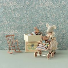 a teddy bear sitting on top of a wooden cart next to two small rocking chairs