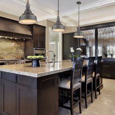 a large kitchen with dark wood cabinets and marble counter tops, along with an island in the middle