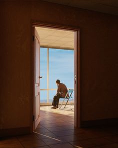 a man sitting on top of a chair in front of an open door looking at the ocean