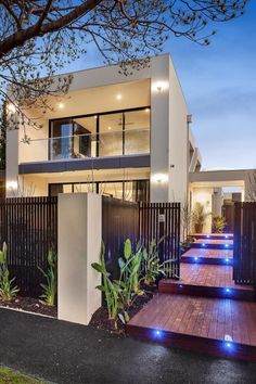 a modern house that is lit up at night with blue lights in the front yard