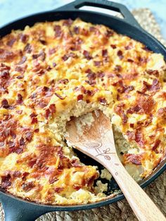 a close up of a casserole in a pan with a wooden spoon