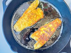 two pieces of fish frying in a skillet