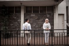 two people standing next to each other in front of a building