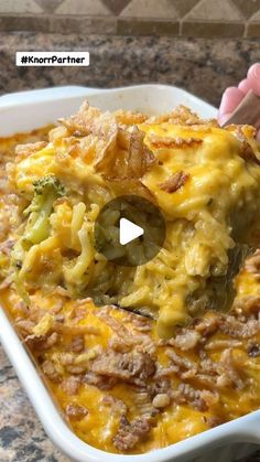 a casserole dish with broccoli and cheese being scooped from the casserole