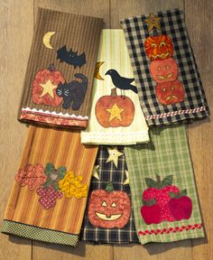 four napkins with pumpkins, apples, and bats on them sitting on a wooden floor