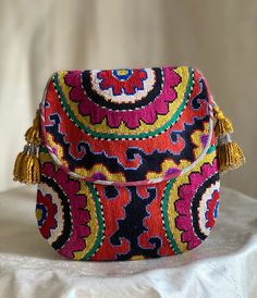 "Smallish size Flat with Flap Silk Petit Point Handbag created and handmade in Uzbekistan. Lined with silk and cotton stripe fabric, hand woven silk straps and tassels with a magnetic snap closure. Each handbag is hand drawn onto cotton canvas, inspired by original designs from Uzbekistan textile history.  8\" high x 7.5\" width, top opening 6\" wide approx. 60\" strap x 3/8\" width.  Can fit largest sizes of iPhone and Android. 100% silk petit point with handwoven silk ikat lining. I can shorte Traditional Multicolor Pouch Shoulder Bag, Traditional Multicolor Woven Bags, Multicolor Traditional Bags With Woven Motifs, Traditional Multicolor Bags With Woven Motifs, Traditional Multicolor Pouch Bag, Multicolor Handwork Pouch Shoulder Bag, Traditional Handwoven Multicolor Embroidered Bag, Multicolor Woven Bags For Festivals, Textile History