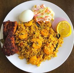 a white plate topped with rice and shrimp next to an egg on top of a wooden table