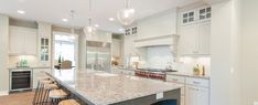 a large kitchen with an island in the middle and two bar stools at the end