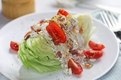 a white plate topped with lettuce covered in tomatoes and other toppings next to a fork