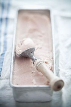 a scoop of ice cream in a metal container with a wooden spatula on top