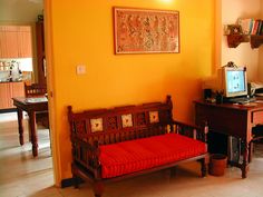 a living room with orange walls and a wooden bench in the middle of the room