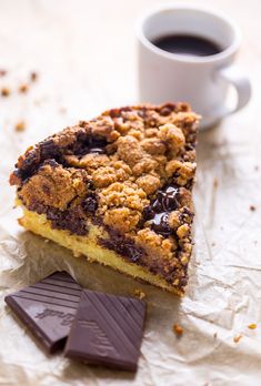 a piece of chocolate chip pie next to a cup of coffee on top of wax paper