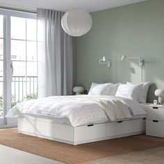 a white bed sitting in a bedroom next to a window with lots of light on it