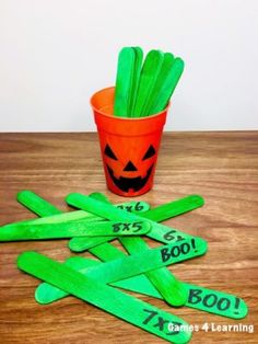 a cup filled with green sticks sitting on top of a wooden table