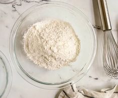 a bowl filled with flour next to a whisk