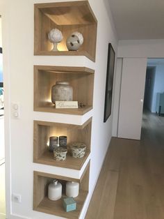 three wooden shelves with vases and other items on them in a white walled room