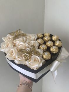 a person holding a heart shaped box filled with chocolates and roses in the shape of a heart