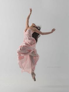 a woman in a pink dress is flying through the air