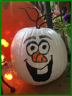 a white pumpkin with an angry face painted on it's side and some lights around it