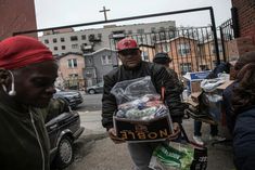 a man holding a box full of items while walking down the street with other people